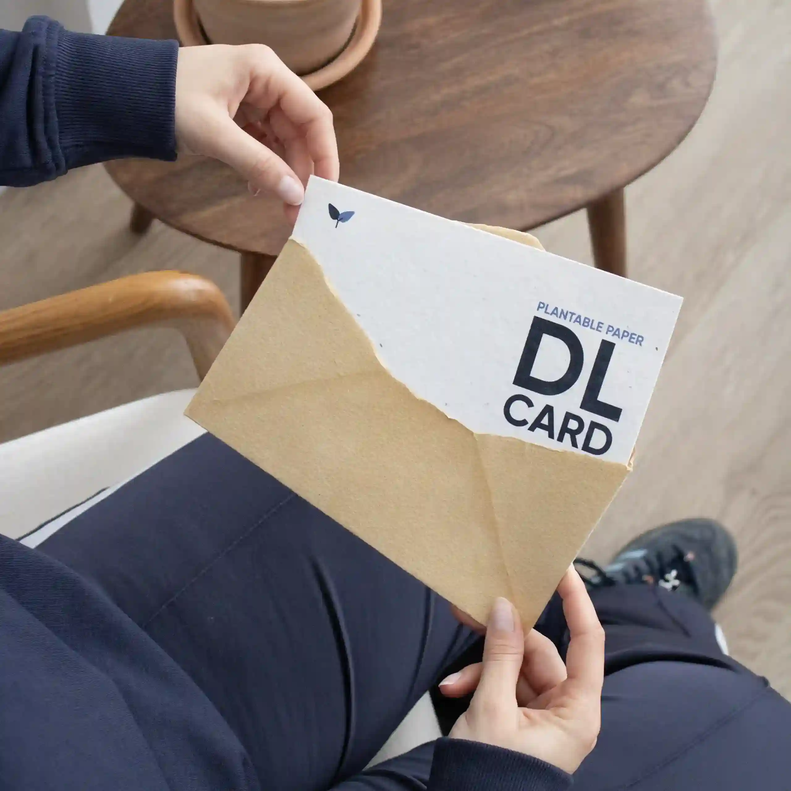 Chica sacando una tarjeta DL impresa en papel plantable de un sobre kraft marrón