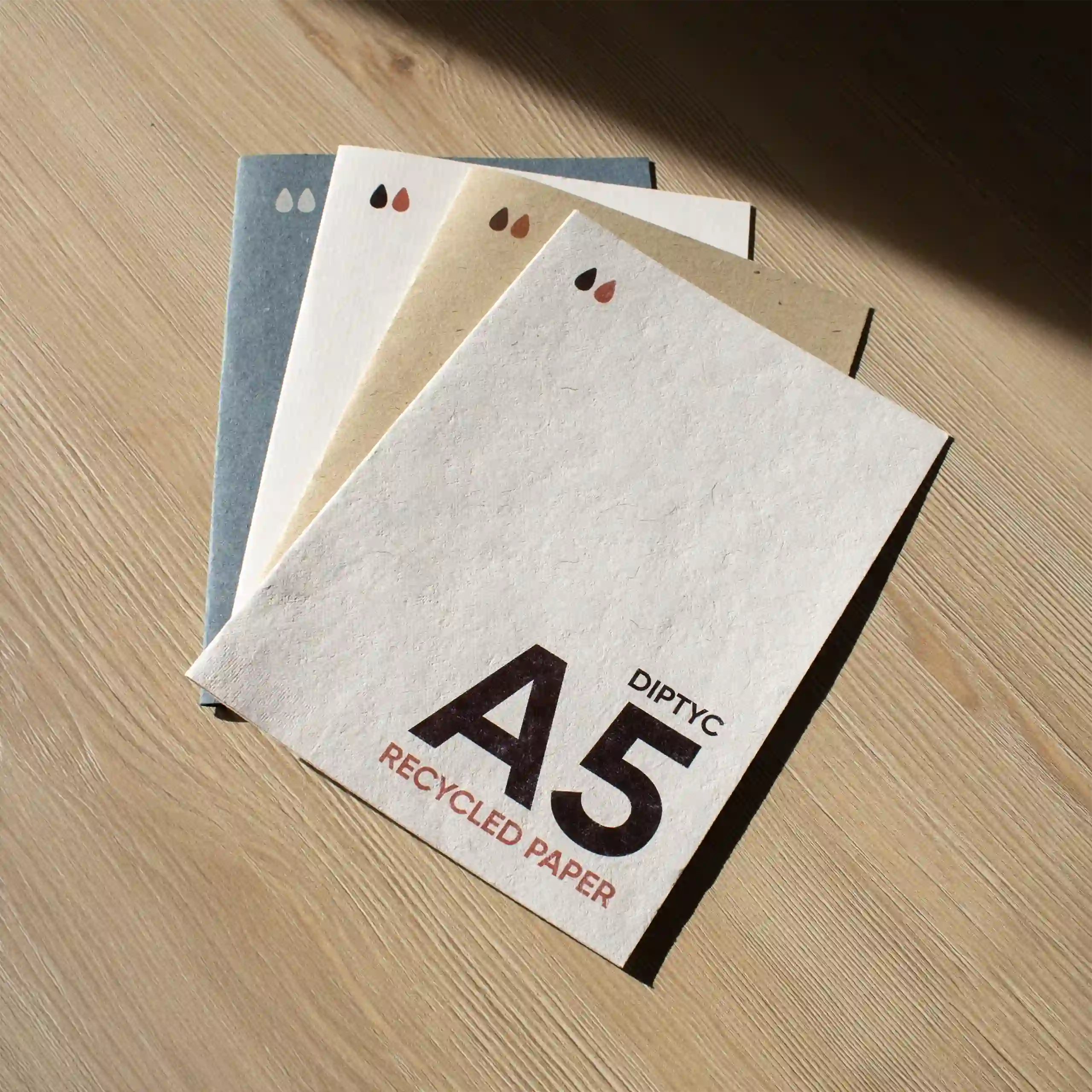 Carte pliante A5 en papier écologique Cuatro dípticos A5 impresos en papel ecológico sobre una superficie de madera