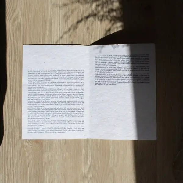 Díptico A5 abierto impreso en papel plantable sobre una superficie con sombras