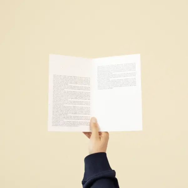 Mano sujetando un díptico A5 abierto impreso en papel plantable