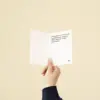 Mano sujetando un díptico A6 abierto impreso en papel plantable