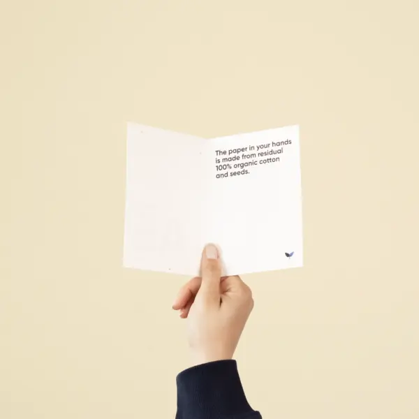 Mano sujetando un díptico A6 abierto impreso en papel plantable