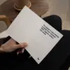 Mano sujetando un díptico A6 abierto impreso en papel plantable