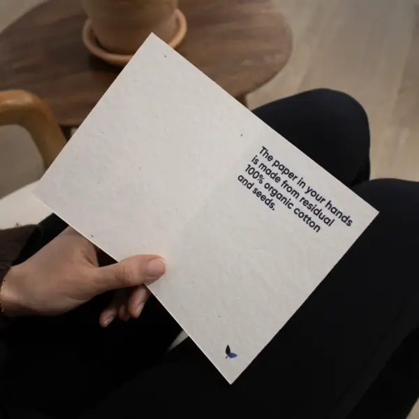 Mano sujetando un díptico A6 abierto impreso en papel plantable