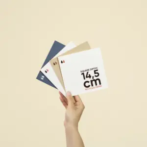 Una mano sujetando cuatro dípticos cuadrados impresos en papel ecológico