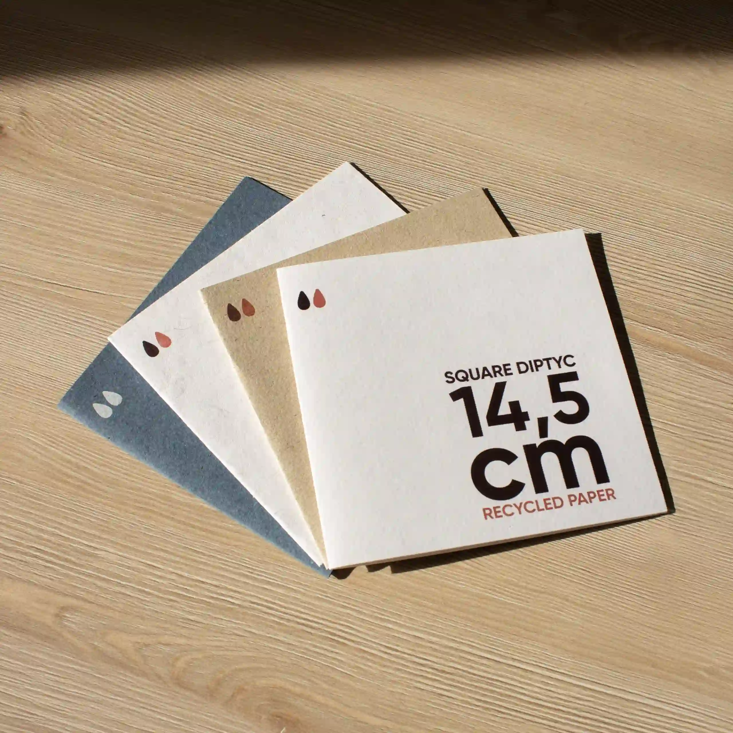 Carte pliante carrée en papier écologique Cuatro dípticos cuadrados impresos en papel ecológico sobre un superficie de madera