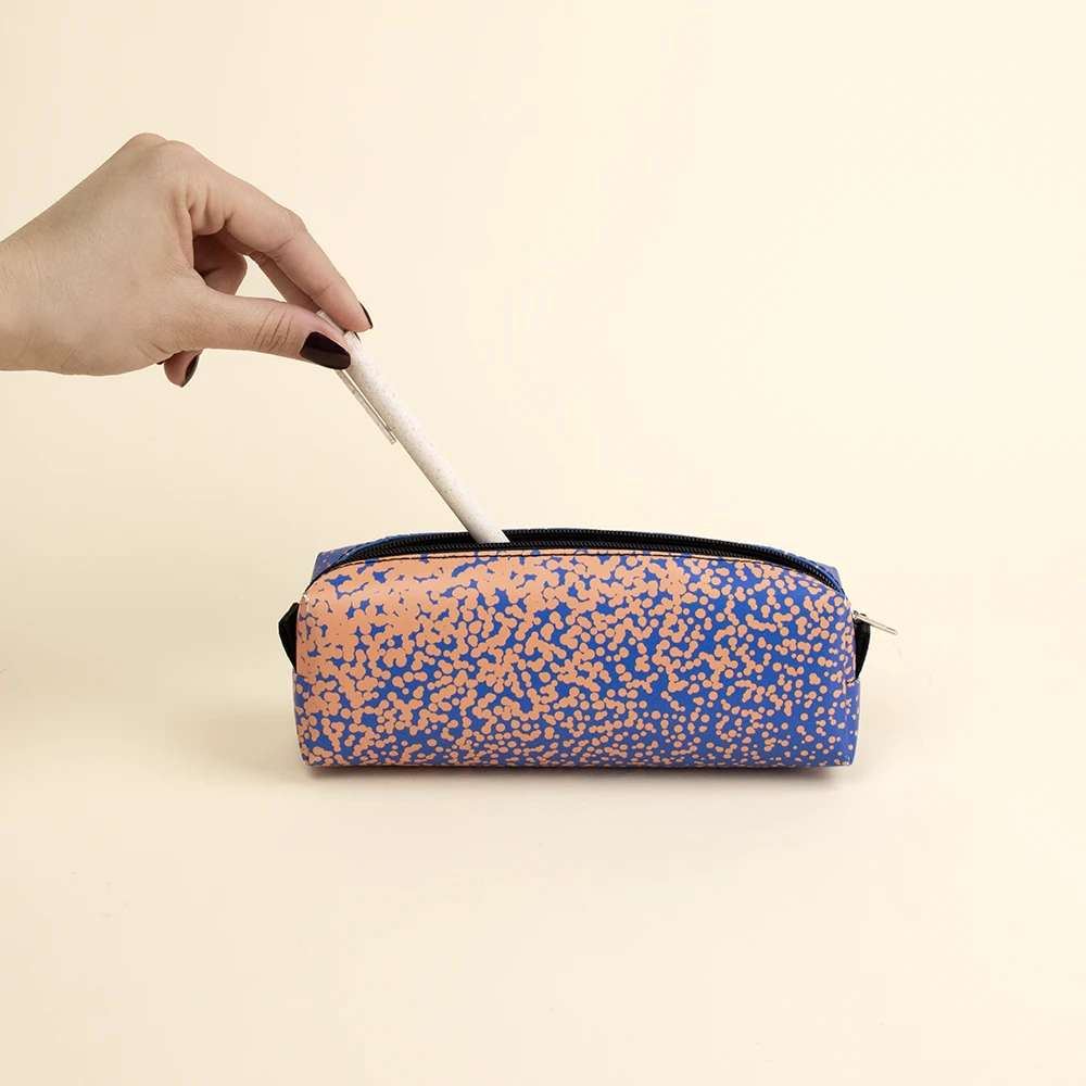 Estuche de lona reciclada DONA Mano metiendo un boli blanco en un estuche de lona reciclada