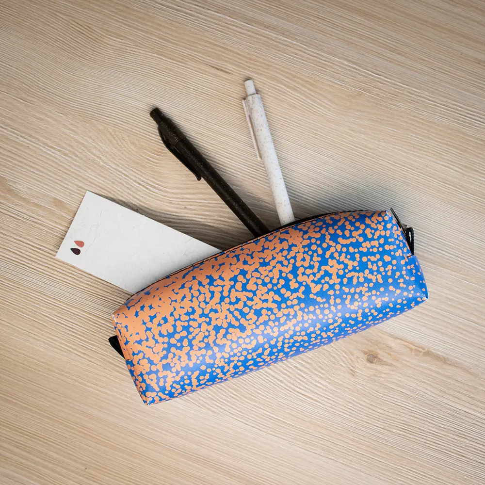 Estuche de lona reciclada DONA Estuche de lona reciclada con dos bolis y un marcapáginas sobre una superficie de madera