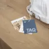 cuatro tarjetas de visita impresas en papeles ecológicos colgadas de una bolsa blanca sobre una superficie de madera