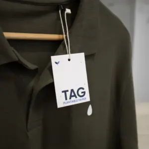 Una etiqueta de ropa impresa en papel plantable colgada de un polo verde