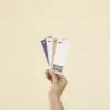 Una mano sujetando cuatro marcapáginas de papel ecológico