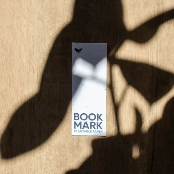 Marcapáginas de papel plantable personalizado sobre una superficie de madera con sombras