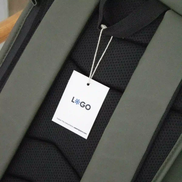 Etiqueta impresa en papel plantable con un marchamo biodegradable blanco colgada de una mochila verde