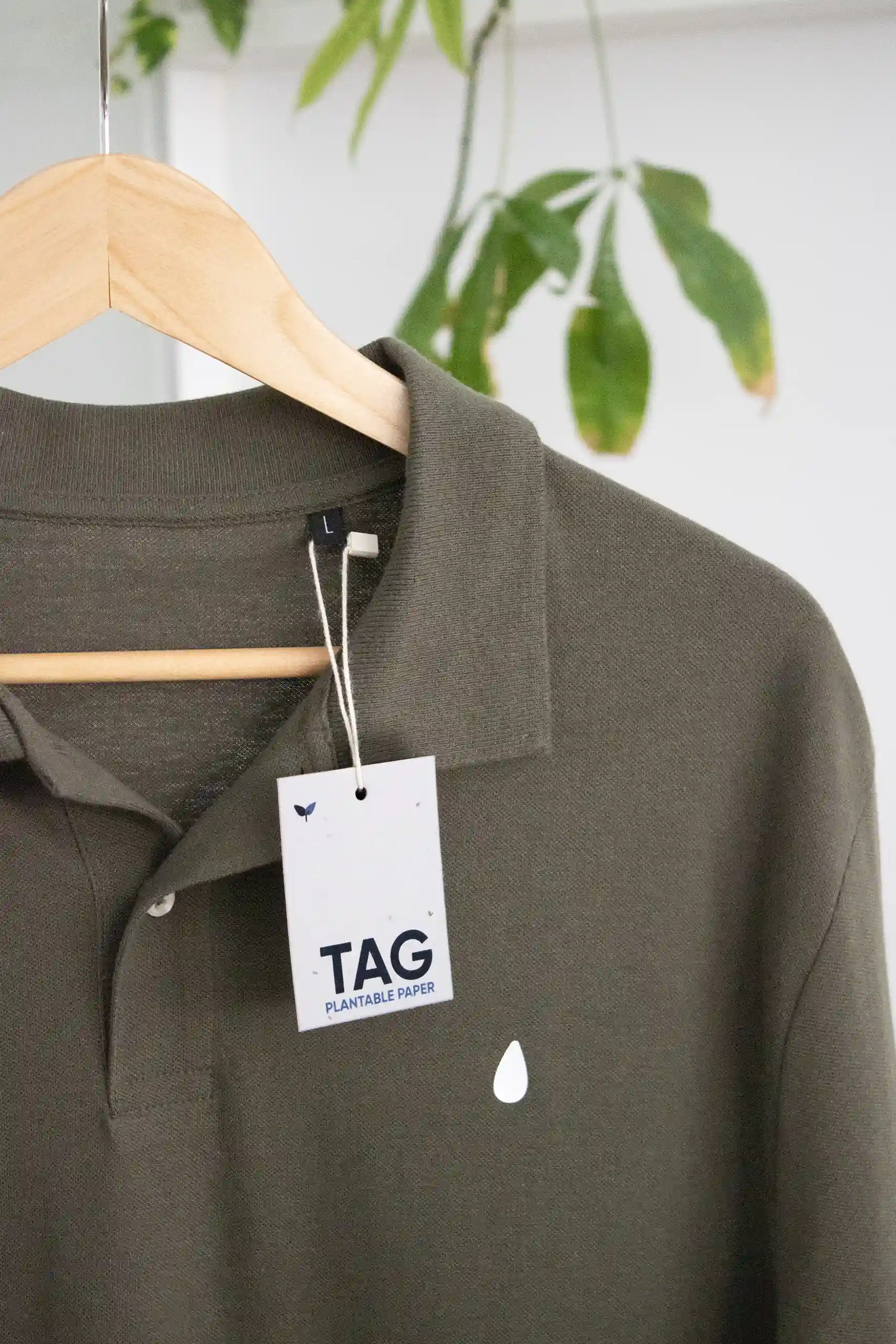 Cordons biodégradables Etiqueta impresa en papel plantable con un marchamo biodegradable blanco colgada de una camiseta verde perchada