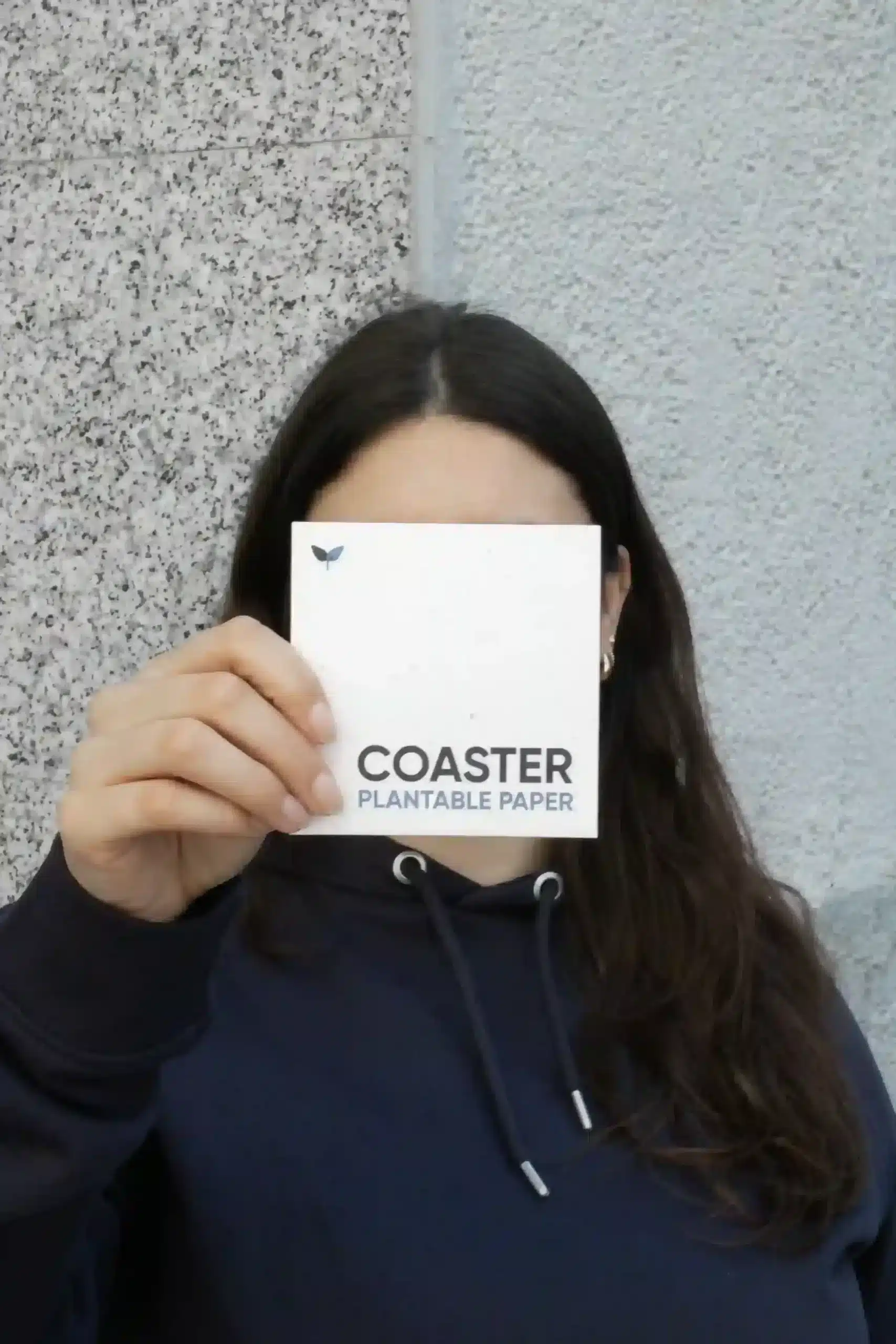 Posavasos de papel plantable Chica mostrando a la cámara un posavasos de papel plantable personalizado