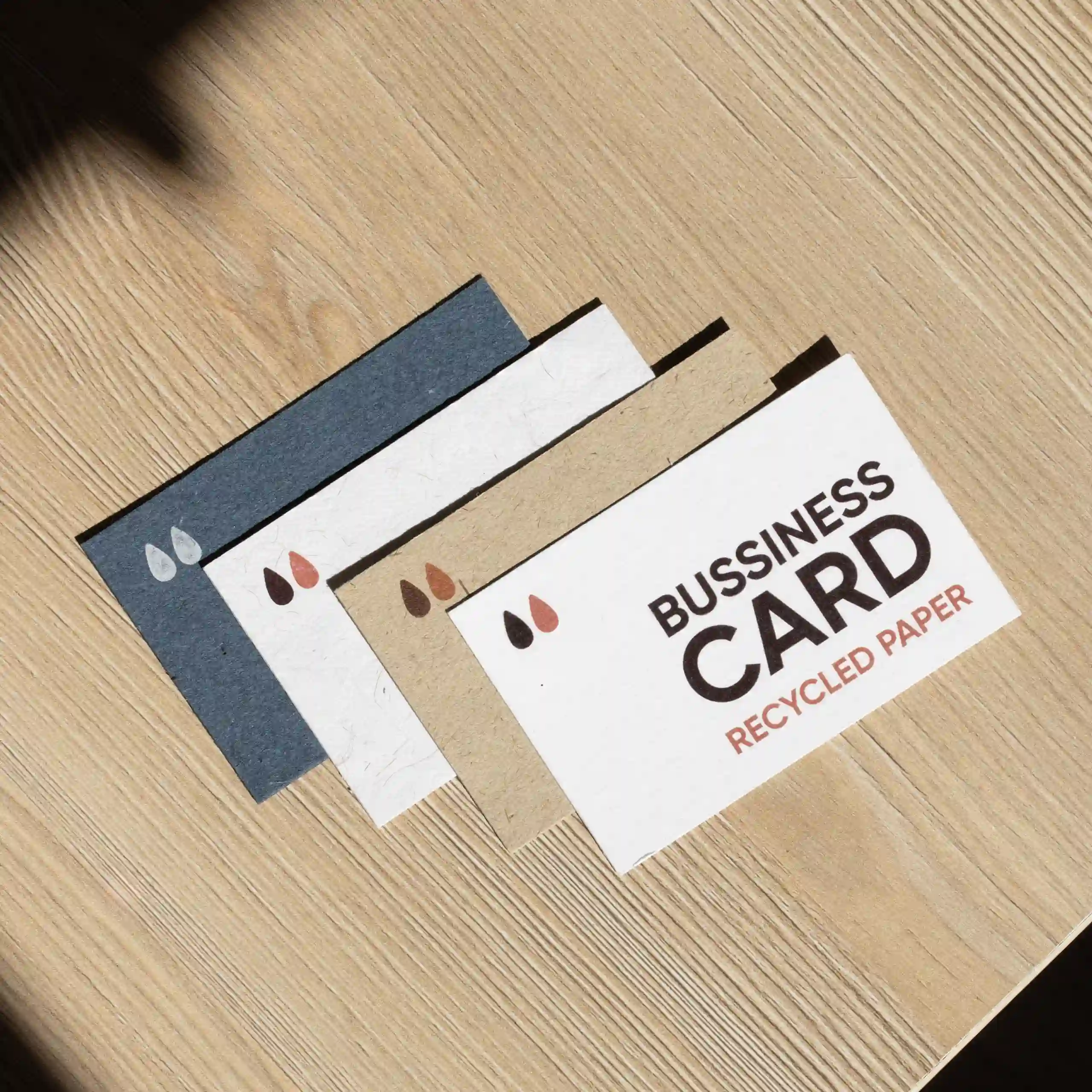 Tarjetas de papel ecológico Cuatro tarjetas de visita impresas en papeles ecológicos sobre una superficie de madera