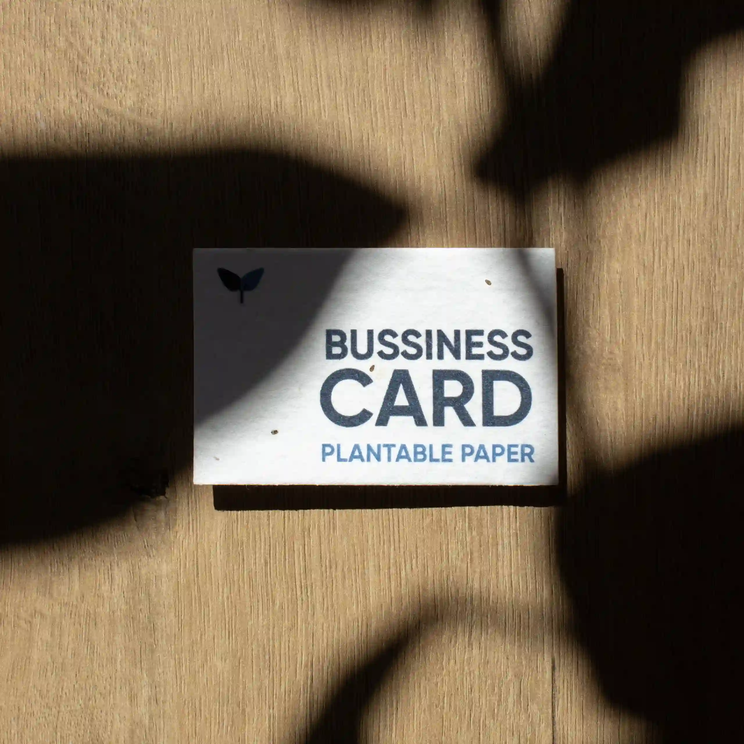 Seed paper business card Tarjeta de visita impresa en papel plantable sobre una superficie de madera con sombras