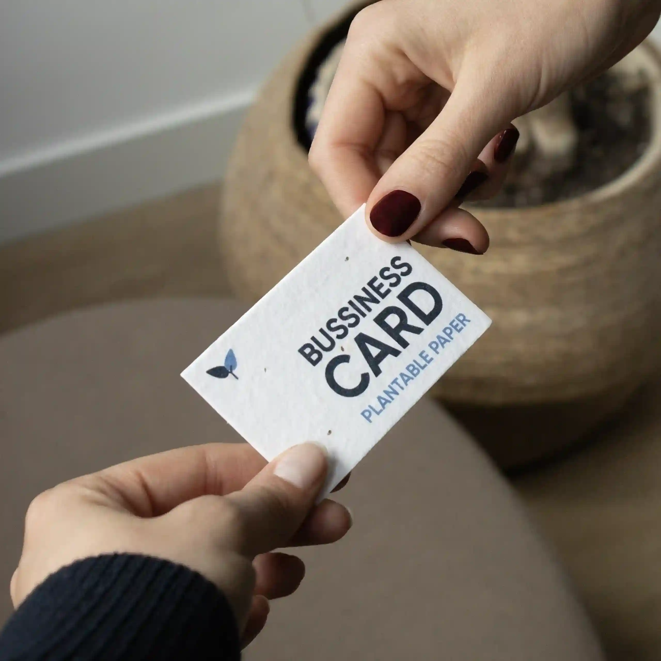 Tarjeta de visita plantable Dos manos sujetando una tarjeta de visita impresa en papel plantable