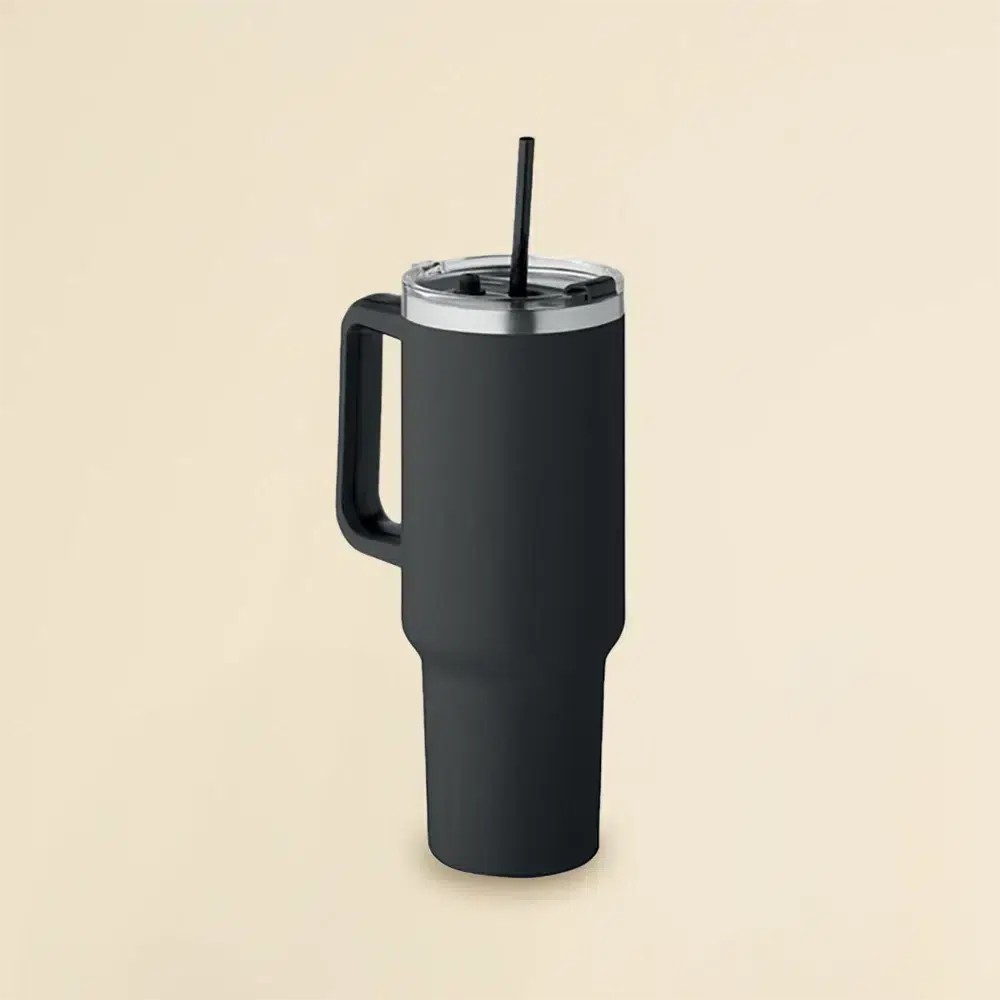 Travel Tumbler: Vaso térmico negro de acero inoxidable con pajita sobre un fondo beige