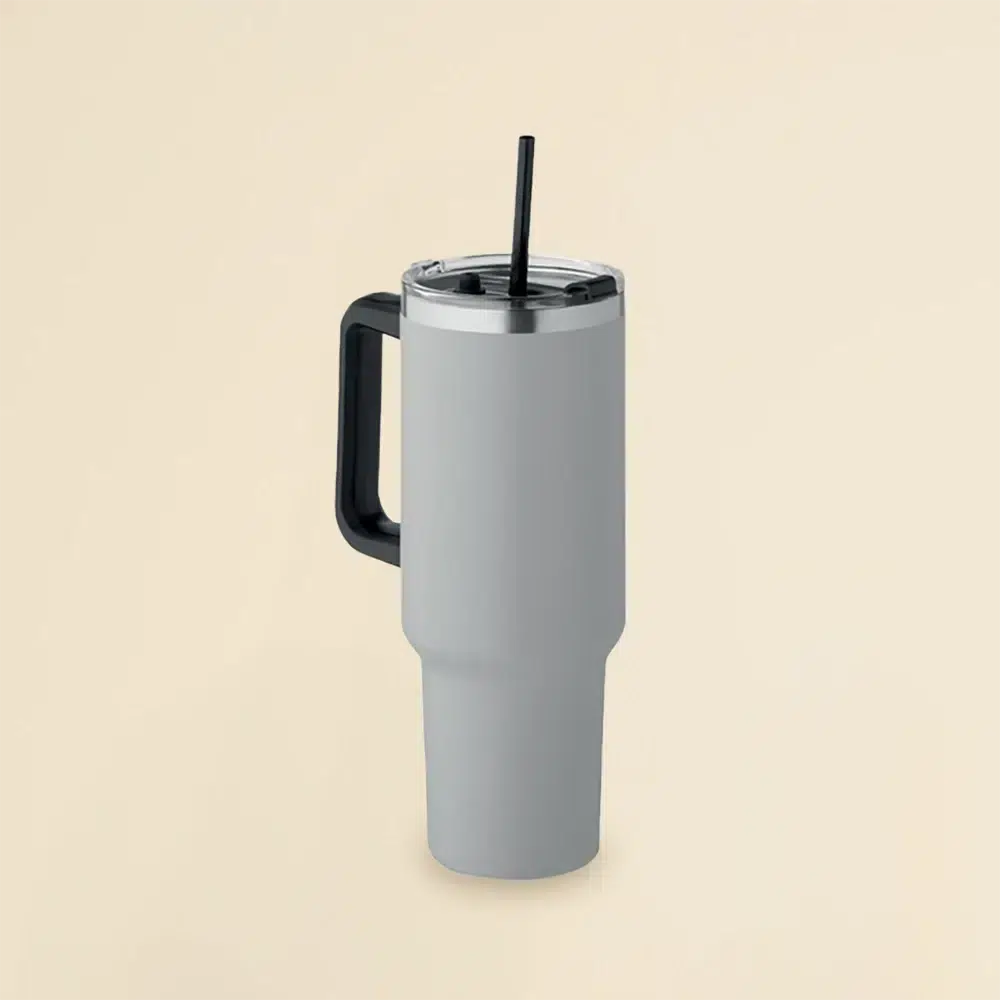 Travel Tumbler: Vaso térmico gris de acero inoxidable con pajita sobre un fondo beige