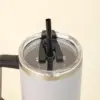 Primer plano de vaso térmico gris de acero inoxidable con pajita sobre un fondo beige