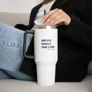 Mano cogiendo la pajita de un vaso térmico de acero inoxidable sobre un sofá