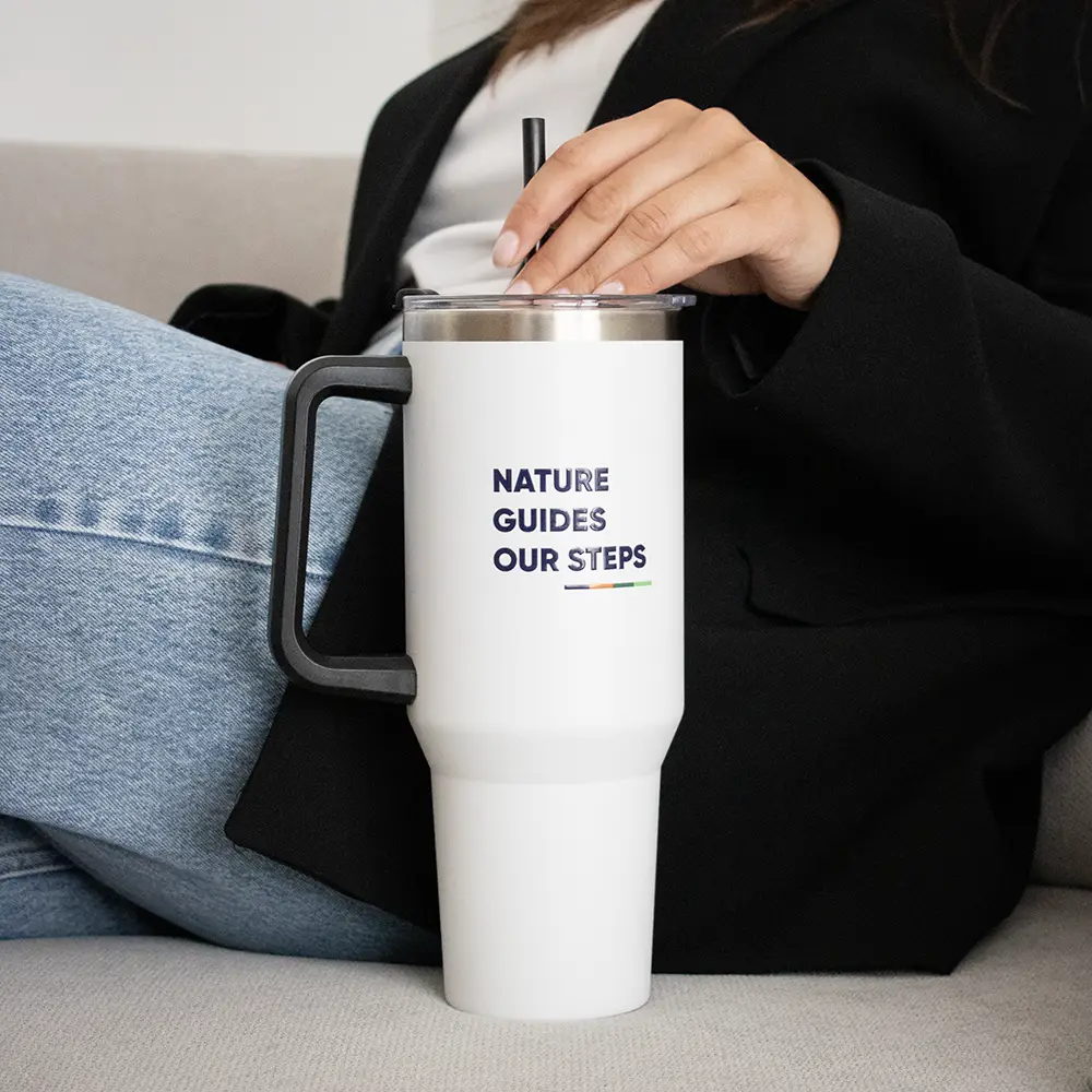 Travel tumbler EVEREST Mano cogiendo la pajita de un vaso térmico de acero inoxidable sobre un sofá