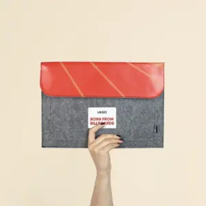 Mano mostrando una funda de portátil personalizada hecha con fieltro y lona roja reciclada