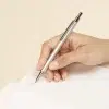 Mano escribiendo sobre un cuaderno con un bolígrafo plateado de aluminio reciclado