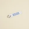 Llavero hecho con lona reciclada blanca personalizado con el texto impreso en azul: "Born from billboards"