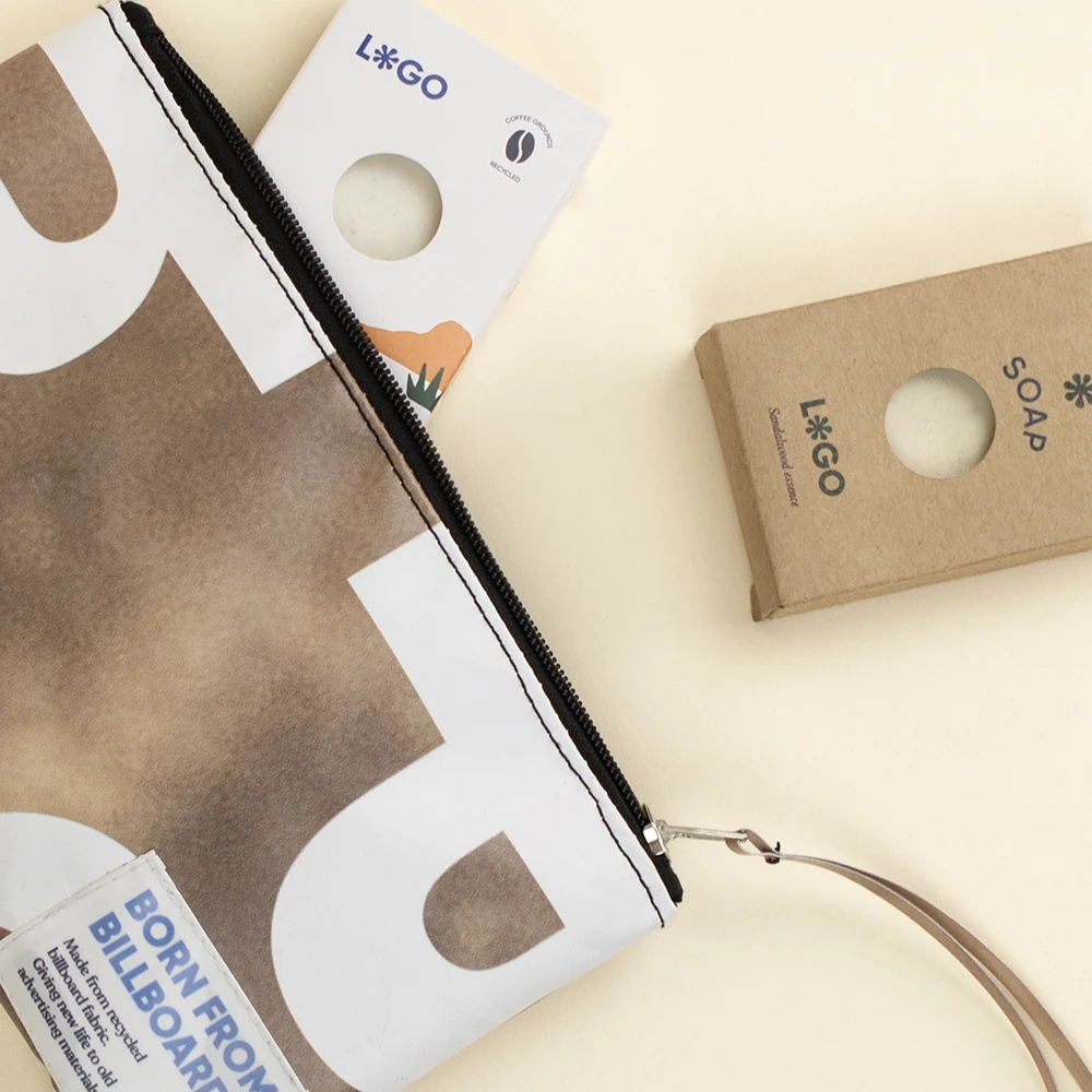Neceser de lona reciclada de color marrón y blanco con la cremallera abierta junto a dos cajas de jabones