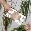 Mano pasando un neceser de lona reciclada de color marrón y blanco a otra mano