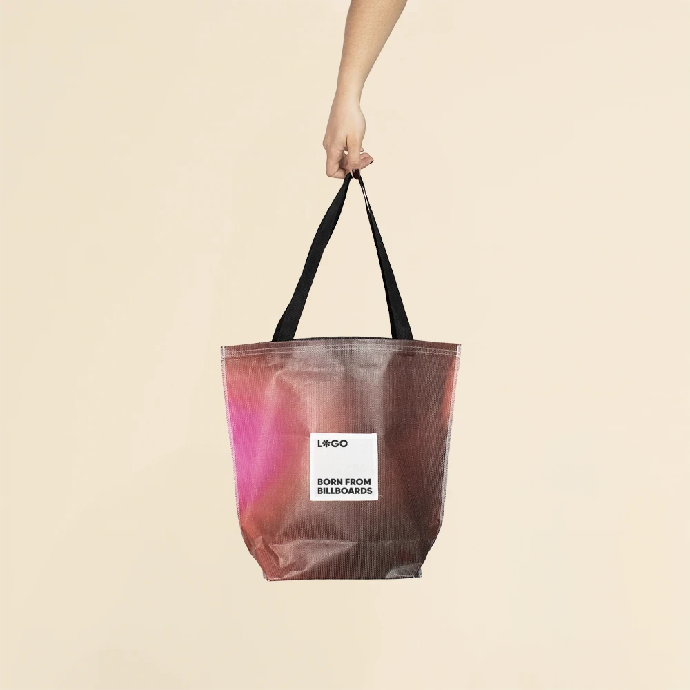 Mano sujetando las asas negras de una tote bag de lona reciclada personalizable