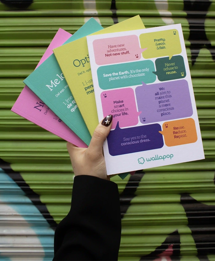 Mano sujetando 4 cuadernos personalizados con la marca de Wallapop