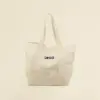 Tote bag de algodón con asas blancas sobre fondo beige