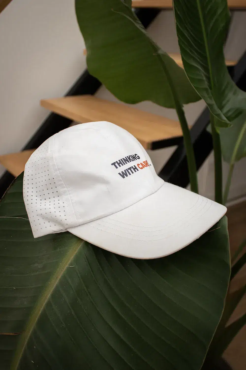 Casquette de sport personnalisée KAPA Gorra con visera personalizable sobre una planta con unas escaleras de fondo