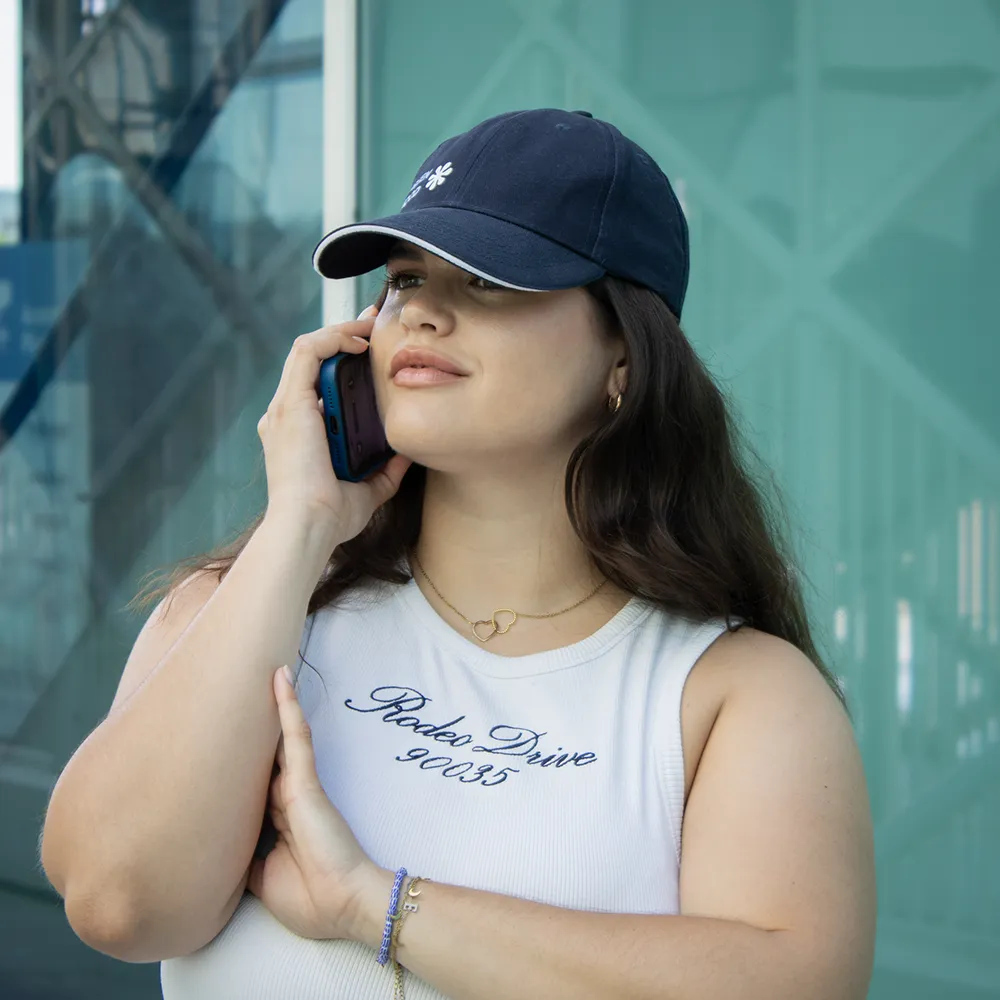 Casquette personnalisée MONDRA Chica hablando por teléfono con una gorra azul con logo lateral
