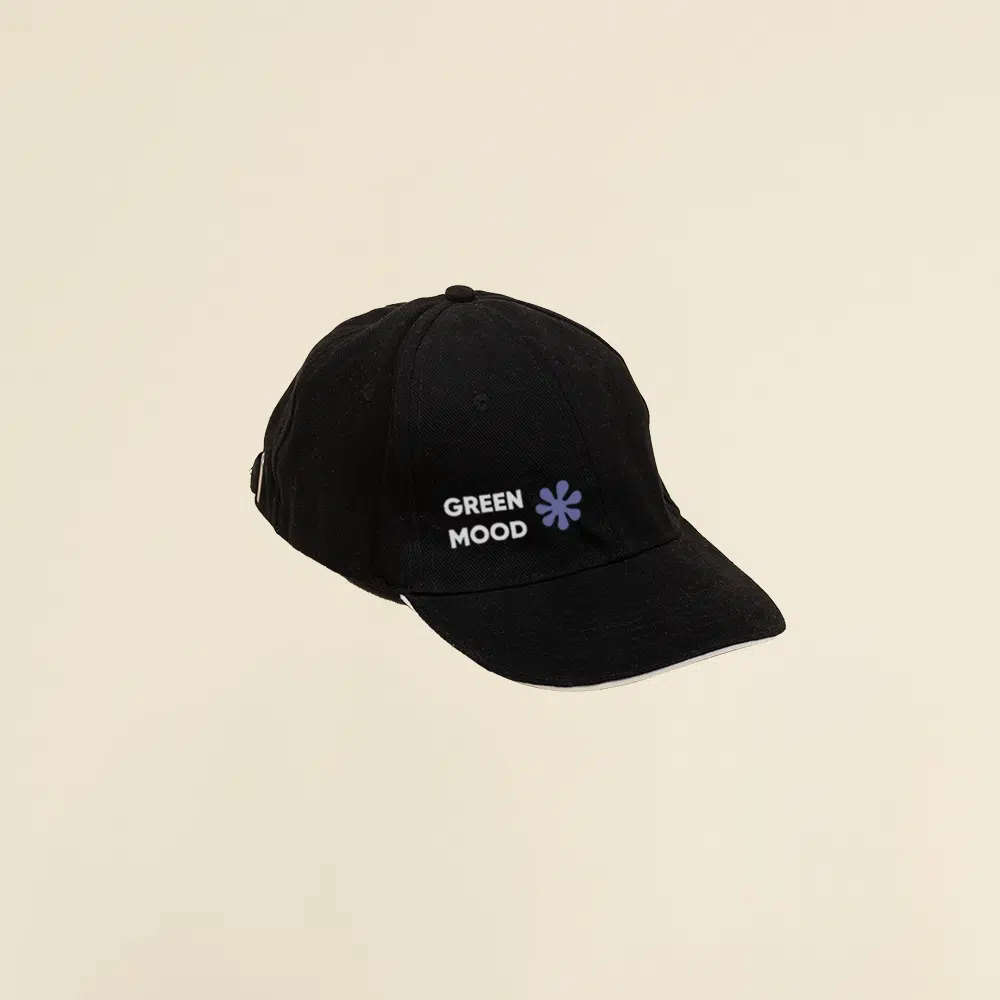 Gorra negra con logo lateral en un fondo beige