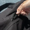 Mano cerrando la cremallera de una bolsa de deporte negra de poliéster reciclado