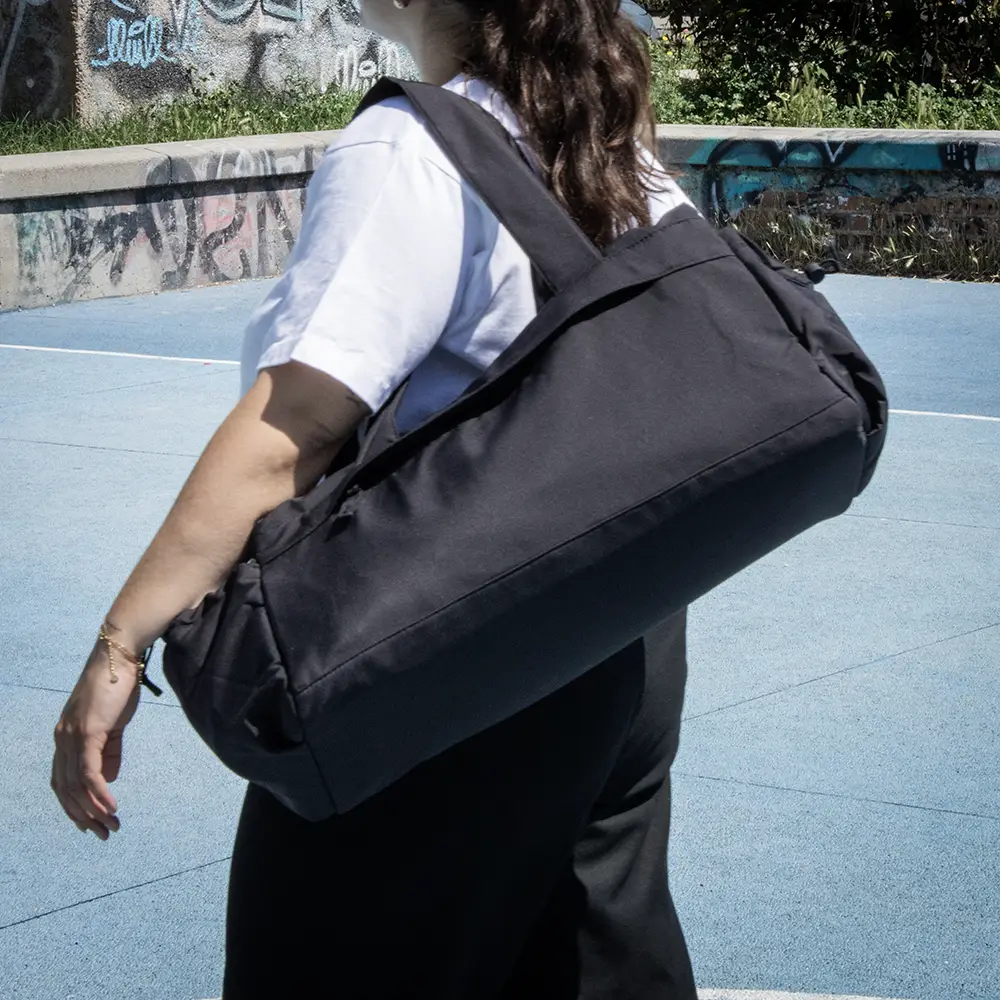 Personalised sustaibable sports bag PULSE Chica con una bolsa de deporte negra de poliƩster reciclado