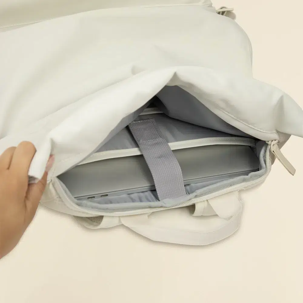 Mochila roll top personalizada ROLA Mano abriendo mochila roll top blanca con un portátil dentro