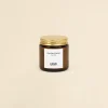Vela aromática personalizada con tapa metálica sobre un fondo beige