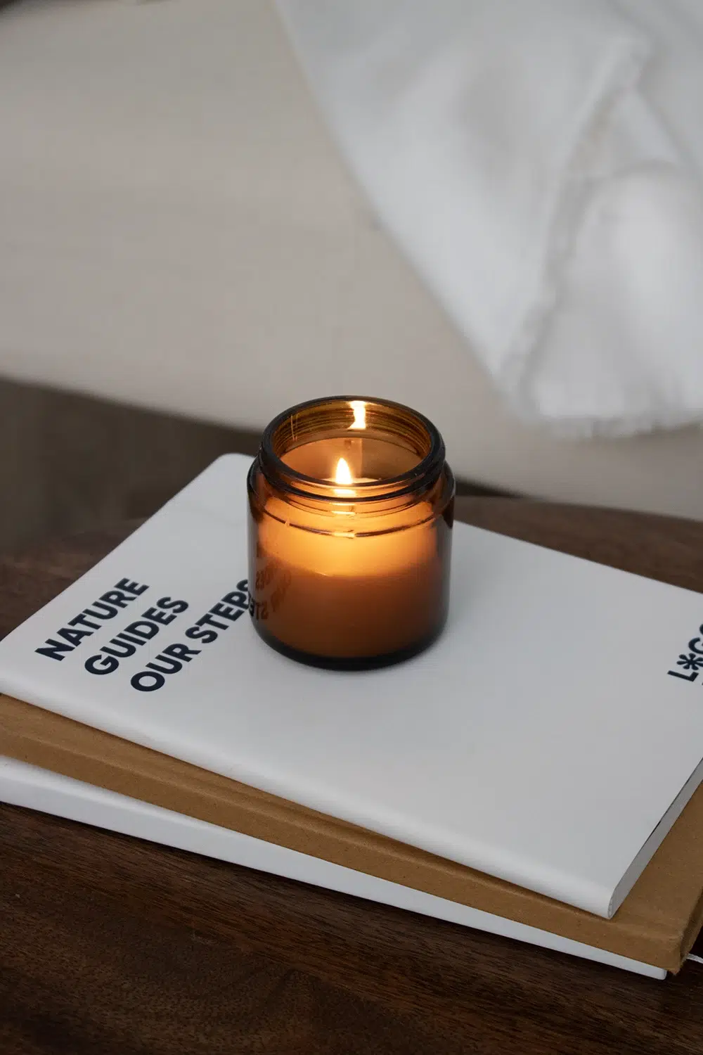 Vela aromática personalizada encendida sobre cuadernos ecológicos