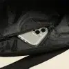 Móvil en el bolsillo de una bolsa negra de viaje de algodón y poliéster reciclado