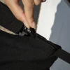 Mano cerrando cremallera de una bolsa negra de viaje de algodón y poliéster reciclado