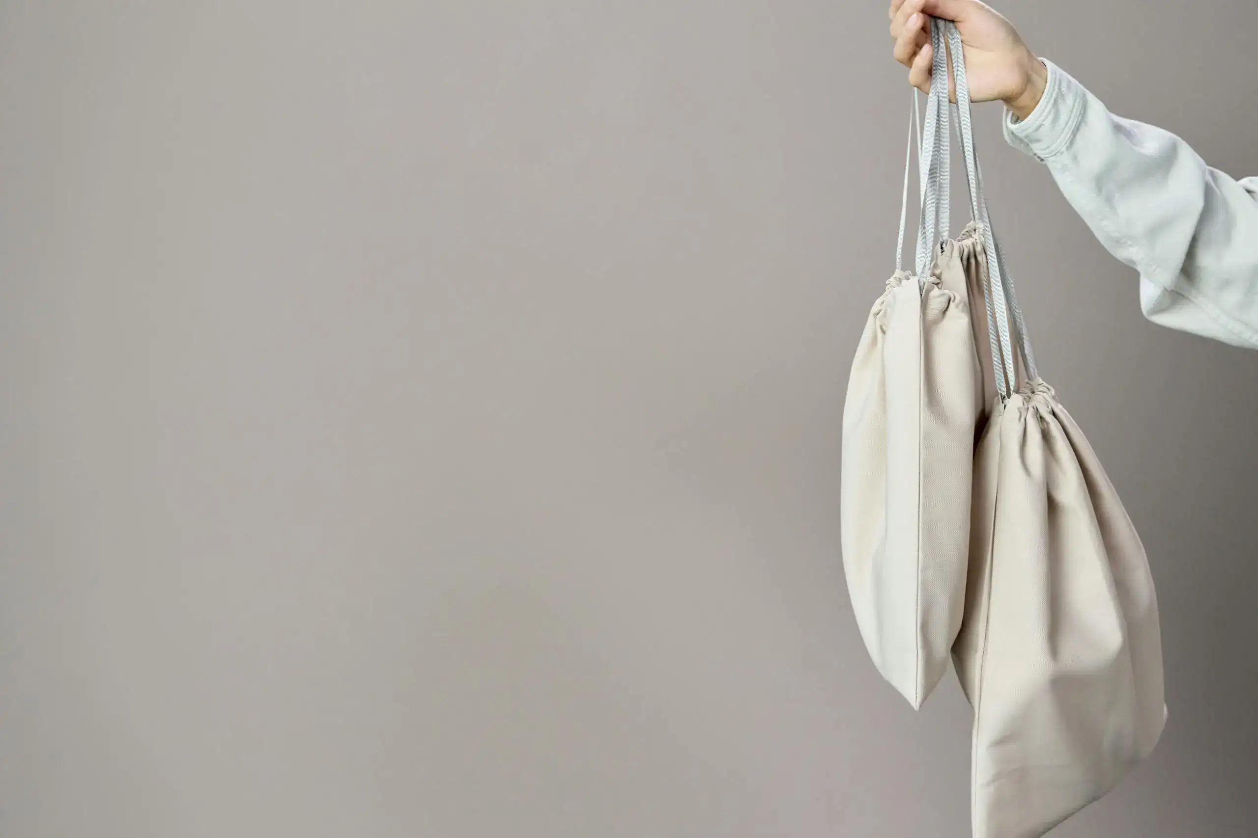 Mano sosteniendo varias bolsas orgánicas desde las asas