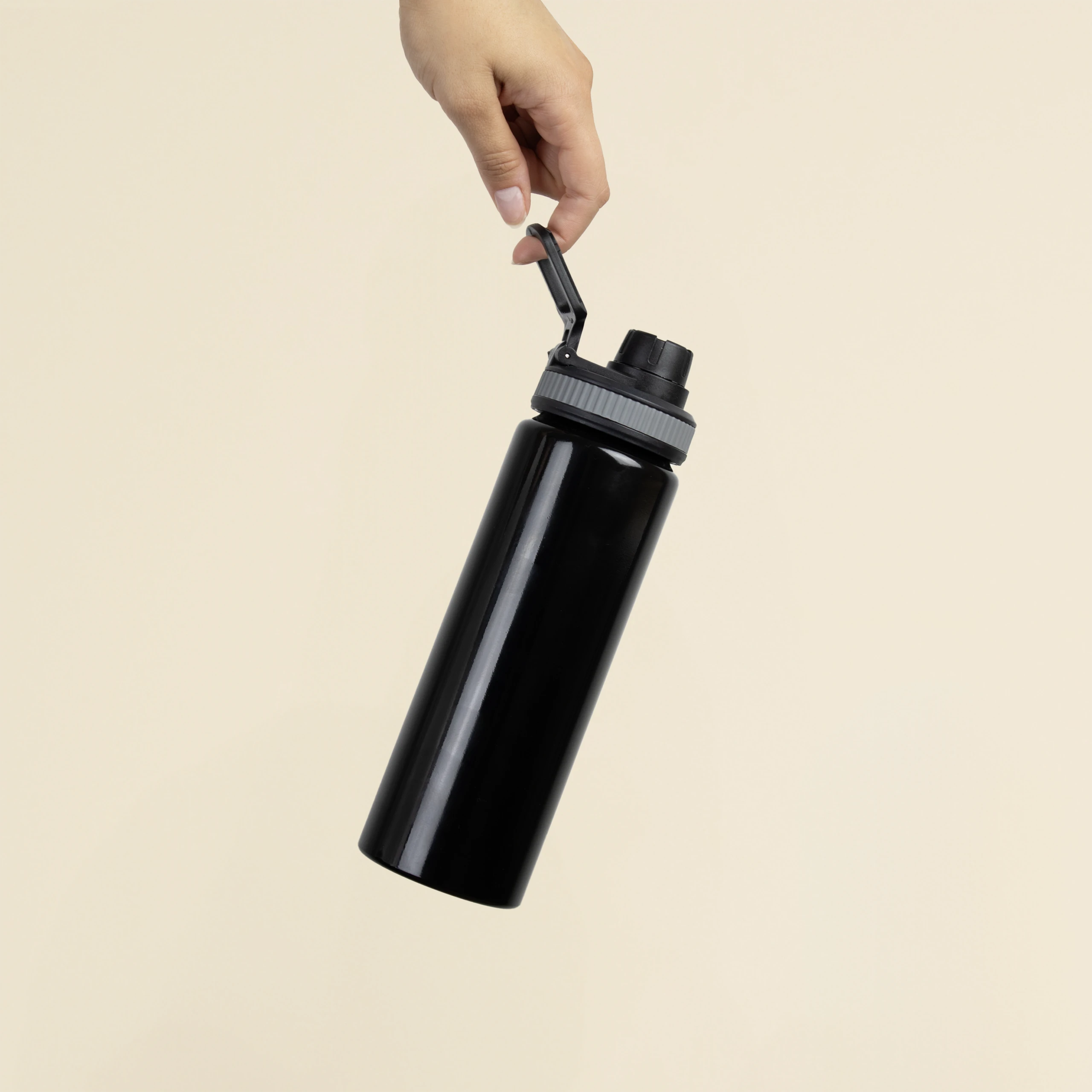 Botella deportiva personalizada BIBO Mano sosteniendo una botella deportiva negra personalizada en aluminio reciclado sobre un fondo beige