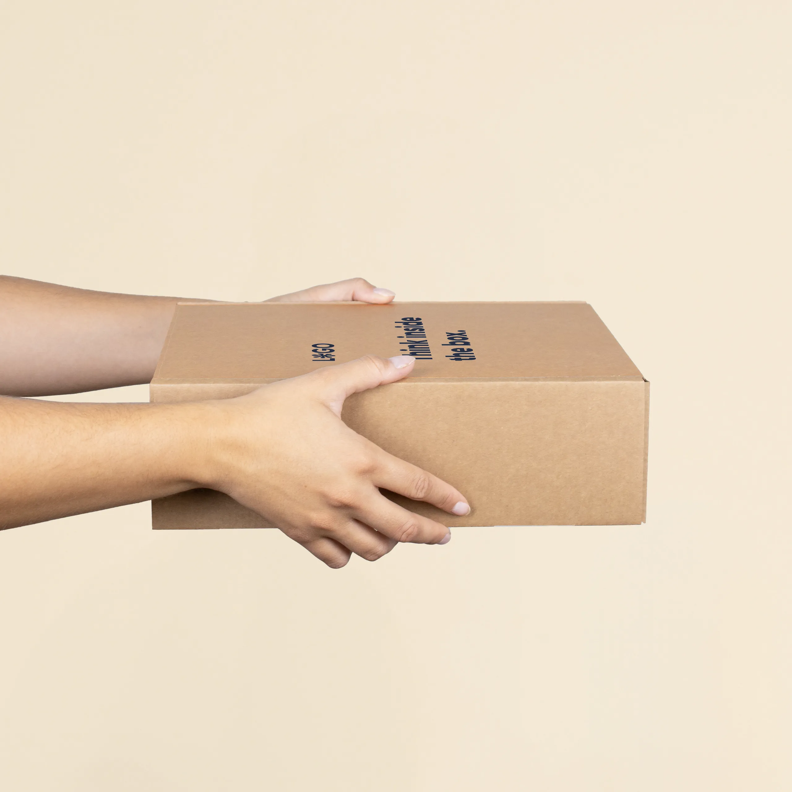Manos sosteniendo una caja M personalizada a un color sobre un fondo beige
