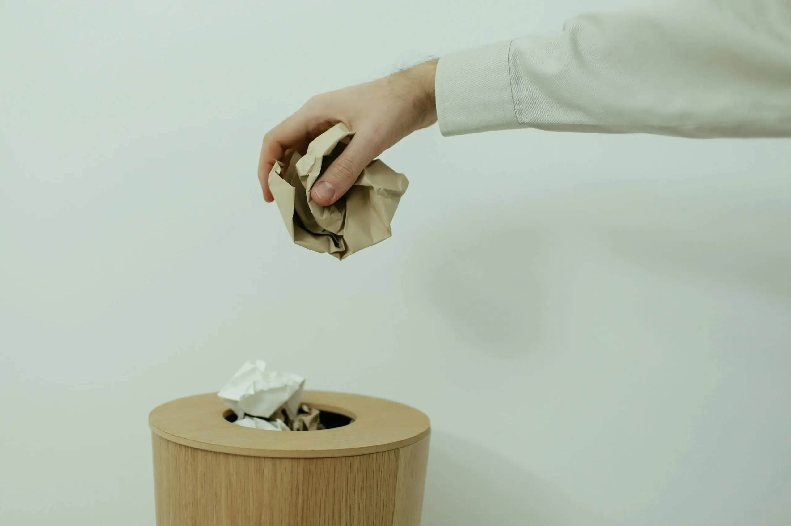 Consejos para reducir residuos Mano tirando un trozo de papel a una papelera