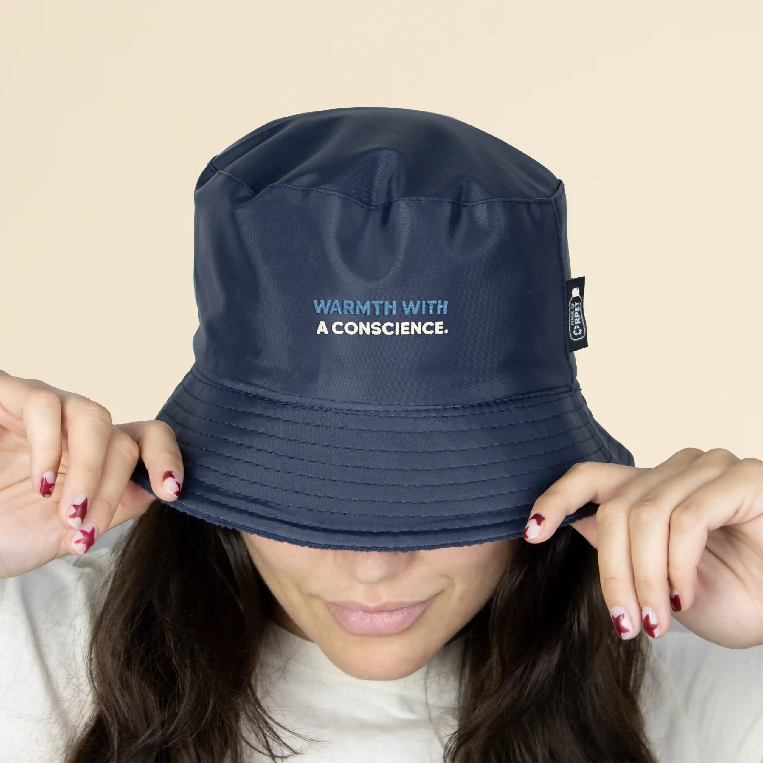 Gorro TWIST azul Chica con un gorro azul impermeable reversible ecológico sobre un fondo beige